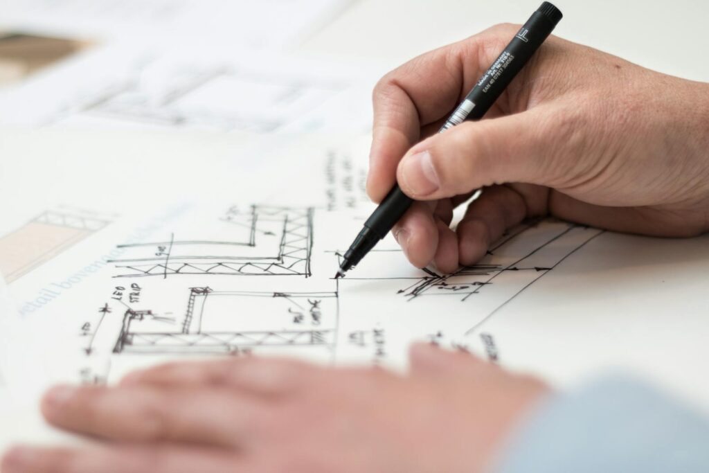 Contactar con Salvador Construcciones Huelva Close-up of hand drawing intricate technical designs on blueprint with pen, ideal for engineering or architecture themes.
