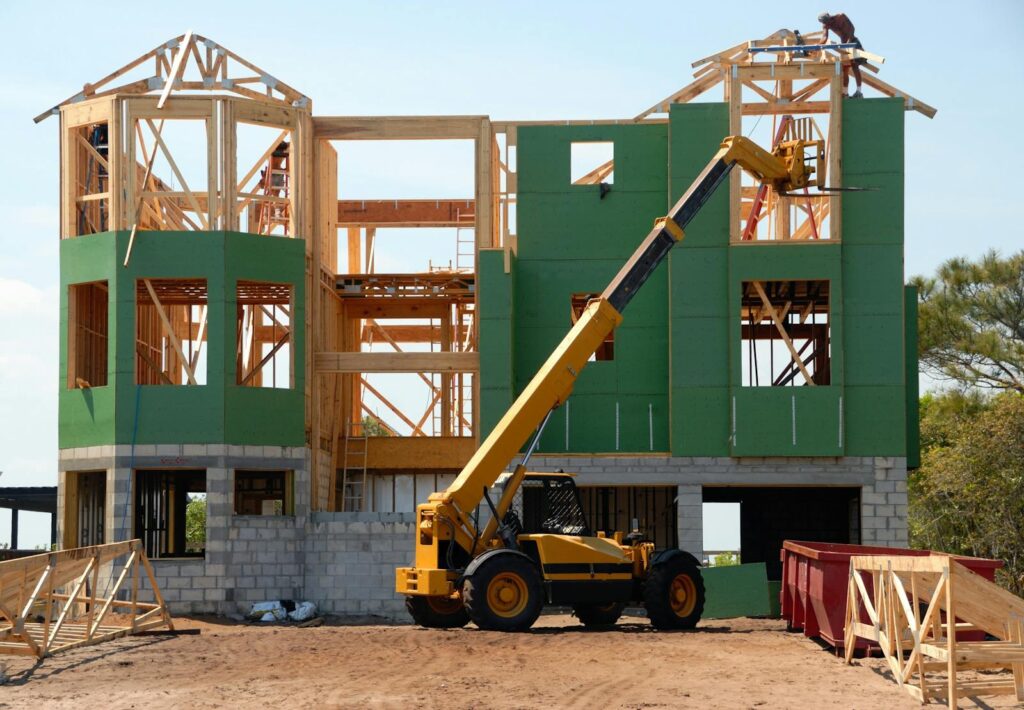 Empresa Reformas Cortedegana a multi-story wooden house under construction using a crane on a sunny day.